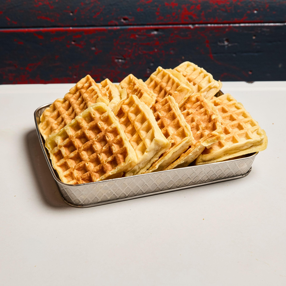 A metal tray filled with golden-brown waffles, ready to be served at Pies 'n' Thighs.